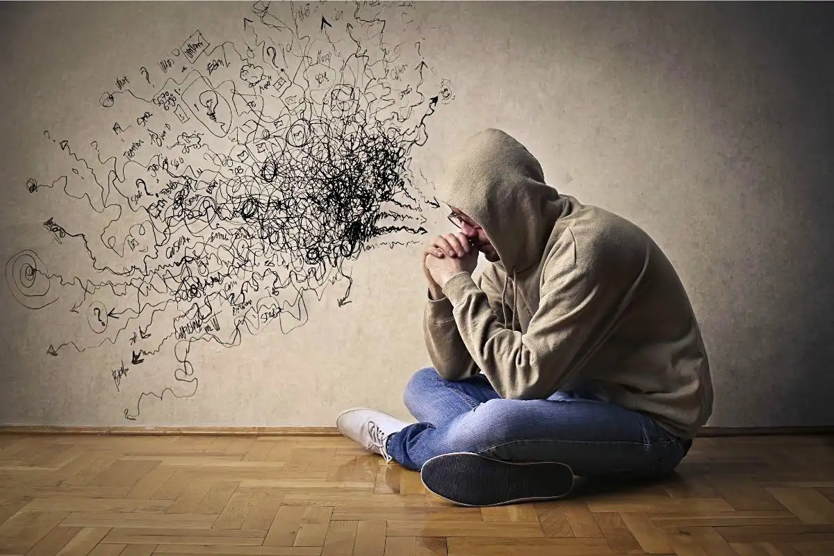 Person sitting on the floor with a drawing of black squiggles representing negative thoughts - Happy Mind Training Blog | Nine Ways to Combat Negative Self-talk
