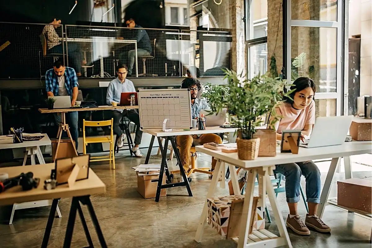 People working in a large open space - Happy Mind Training Blog | Why People Thrive in Coworking Spaces