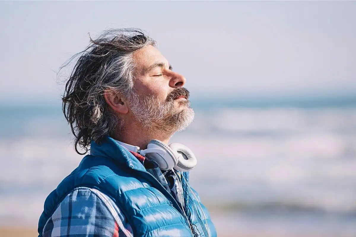 Man with eyes closed having a deep breath on the beach - Happy Mind Training Blog | Nine Ways to Combat Negative Self-talk