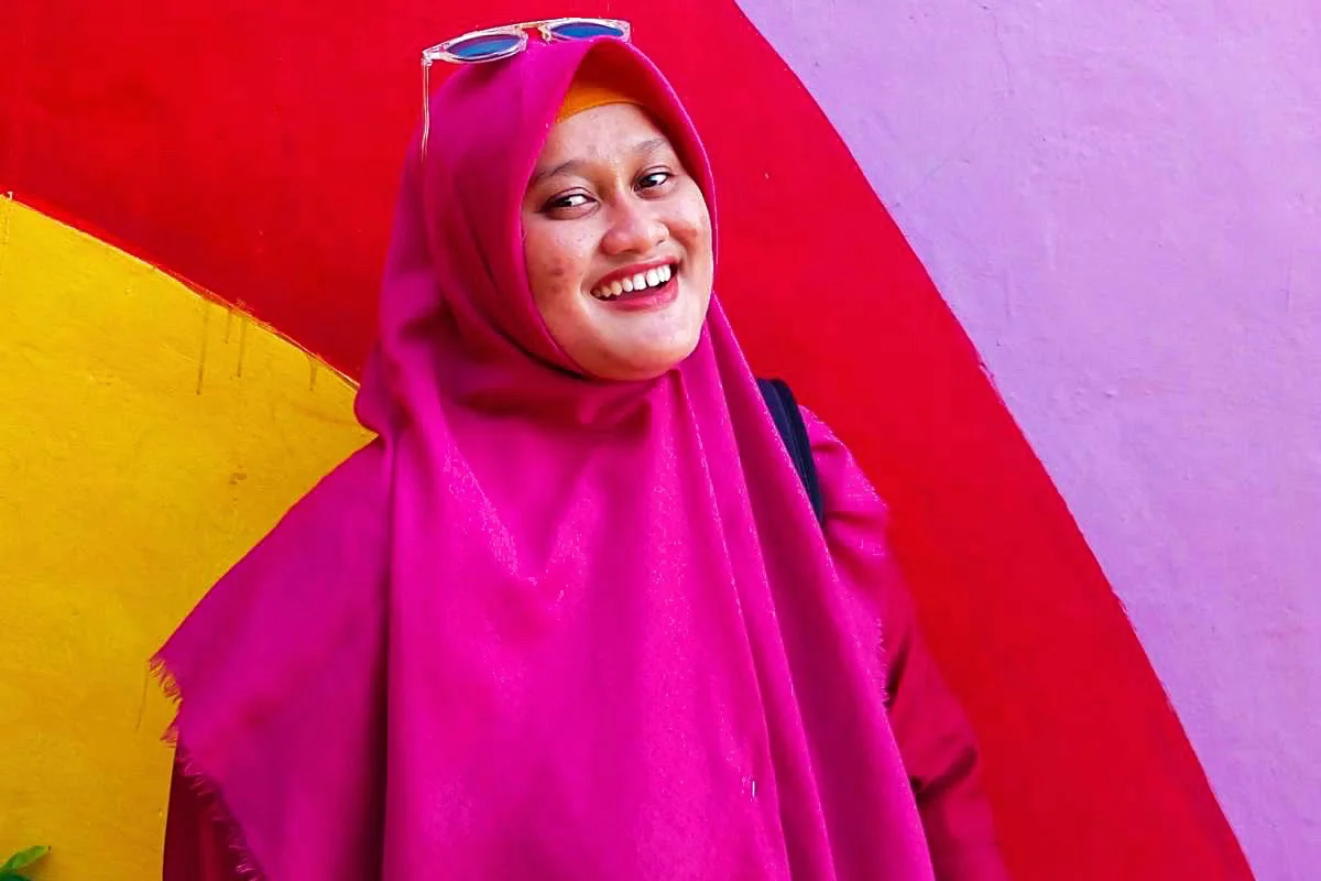 Women wearing a hijab in front of a multicoloured wall