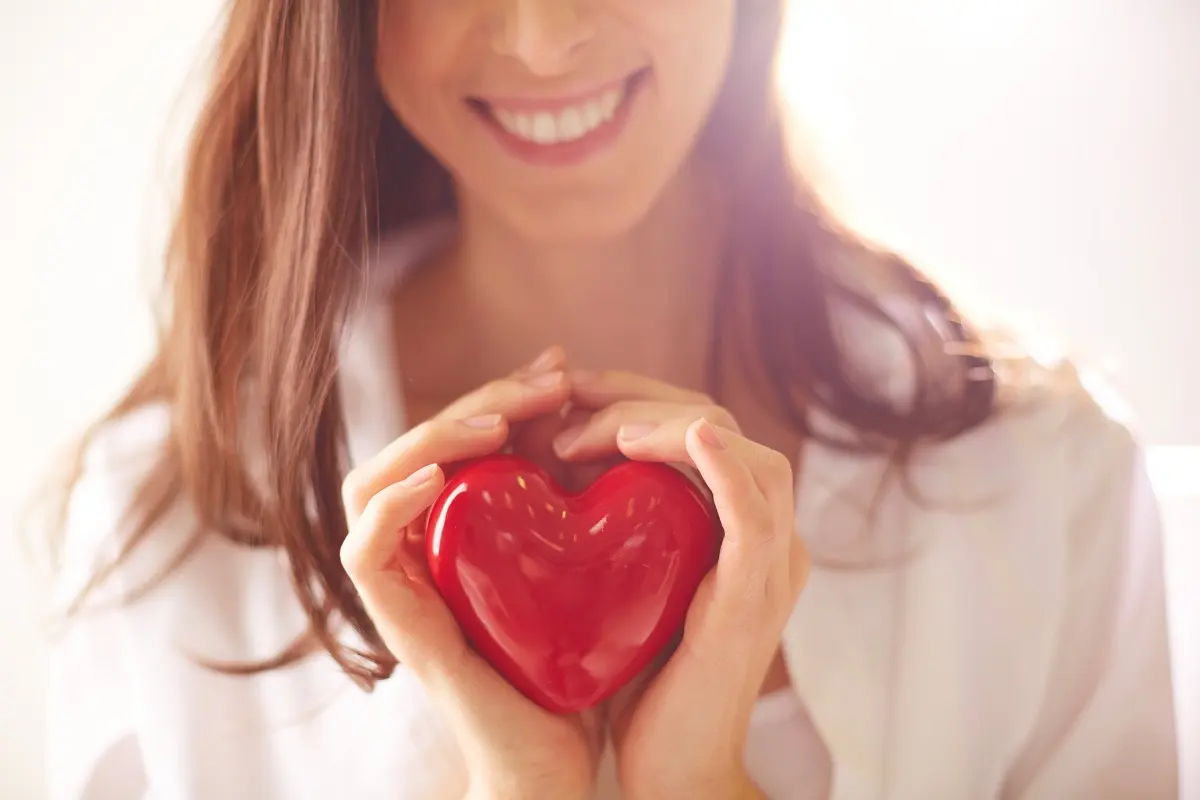 Woman smiling holding a plastic red heart in her hands