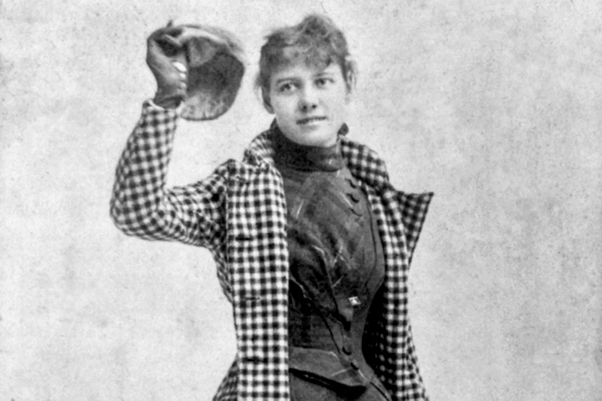 B&W photo of woman holding up a hat in her right hand