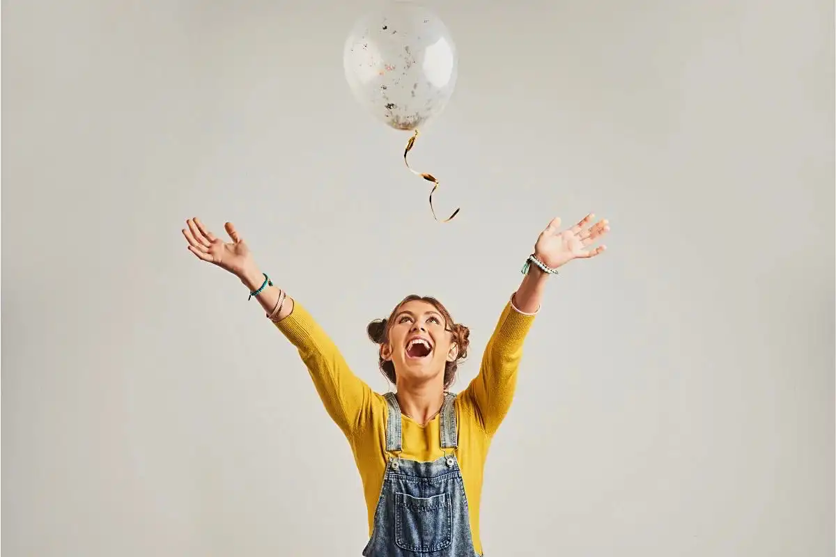 Happy woman throwing a balloon in the air - Happy Mind Training Blog | Nine Ways to Combat Negative Self-talk