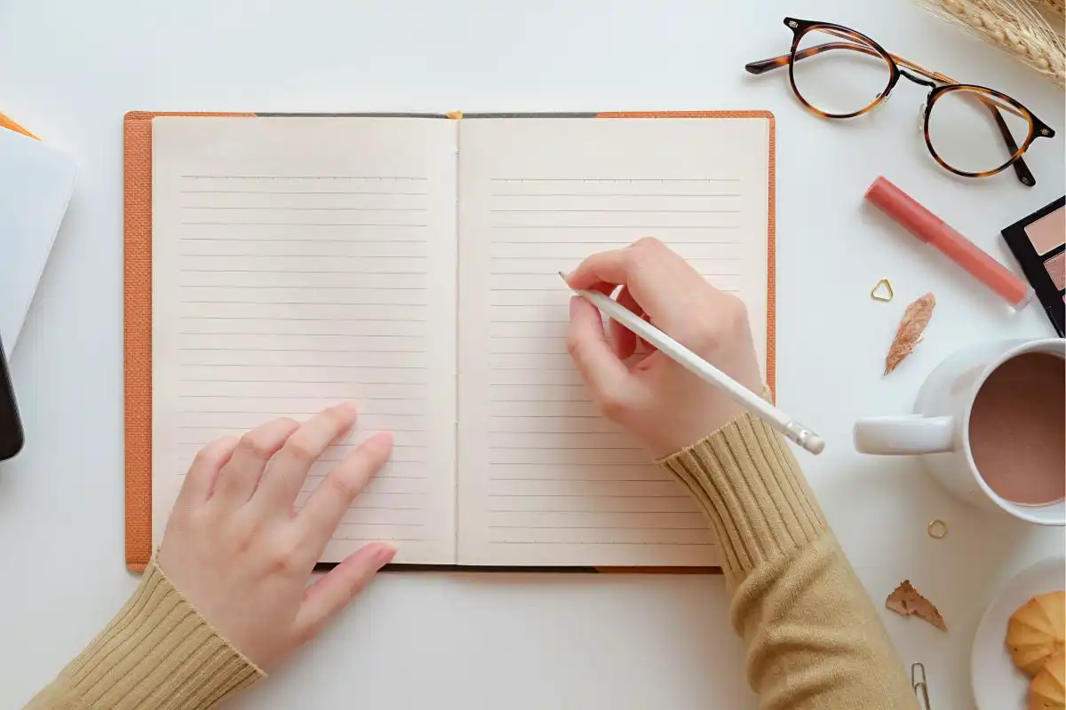 Close up of a person about to start writing on a notebook- Happy Mind Training Blog | How to Start Journaling