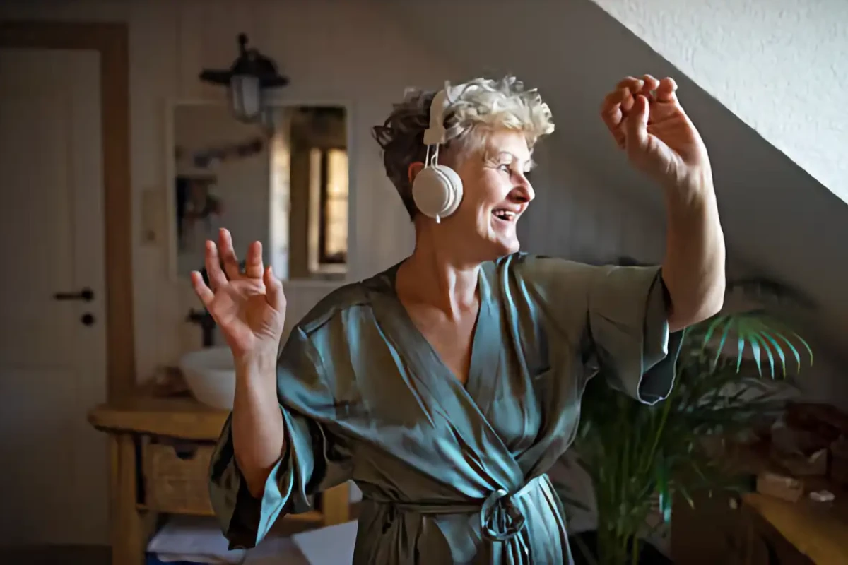 Smiling woman dancing while listening to music on her headphones - HappyMind Training Blog | Pouring From an Empty Cup