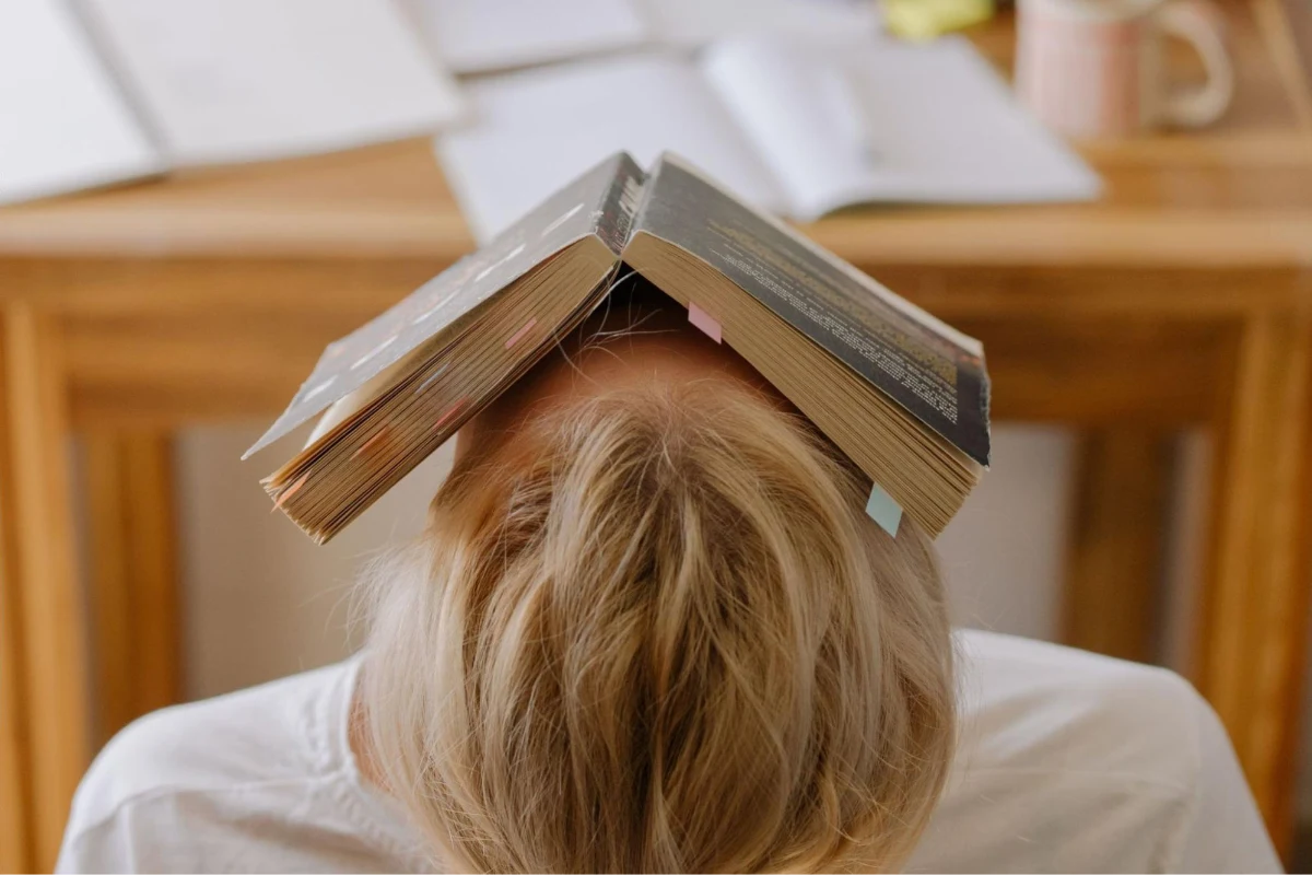 Person with head facing up and a book covering their face | HappyMind Training Blog | Recognising Stress