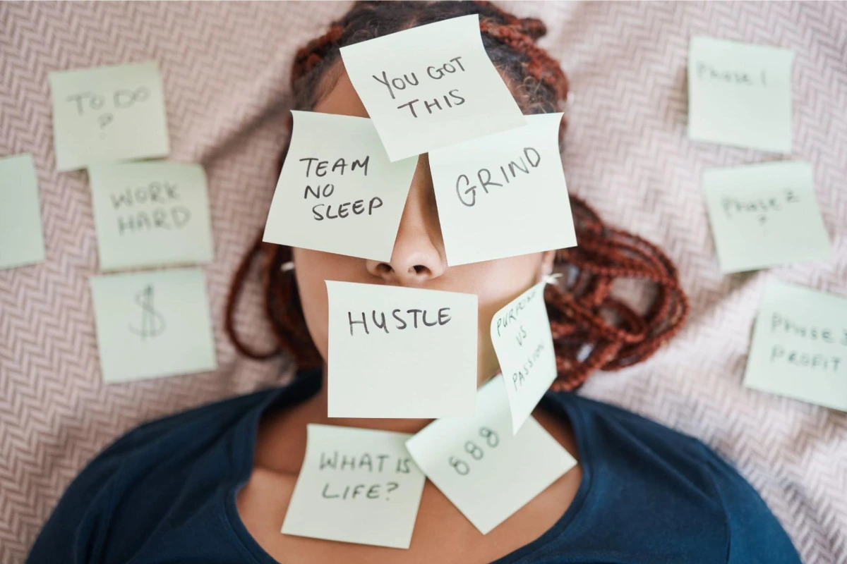 Person with face covered with sticky notes saying "you got this", "Grind", Team no sleep", "hustle", "what is life" and more | Happy Mind Training Blog | Recognising Stress