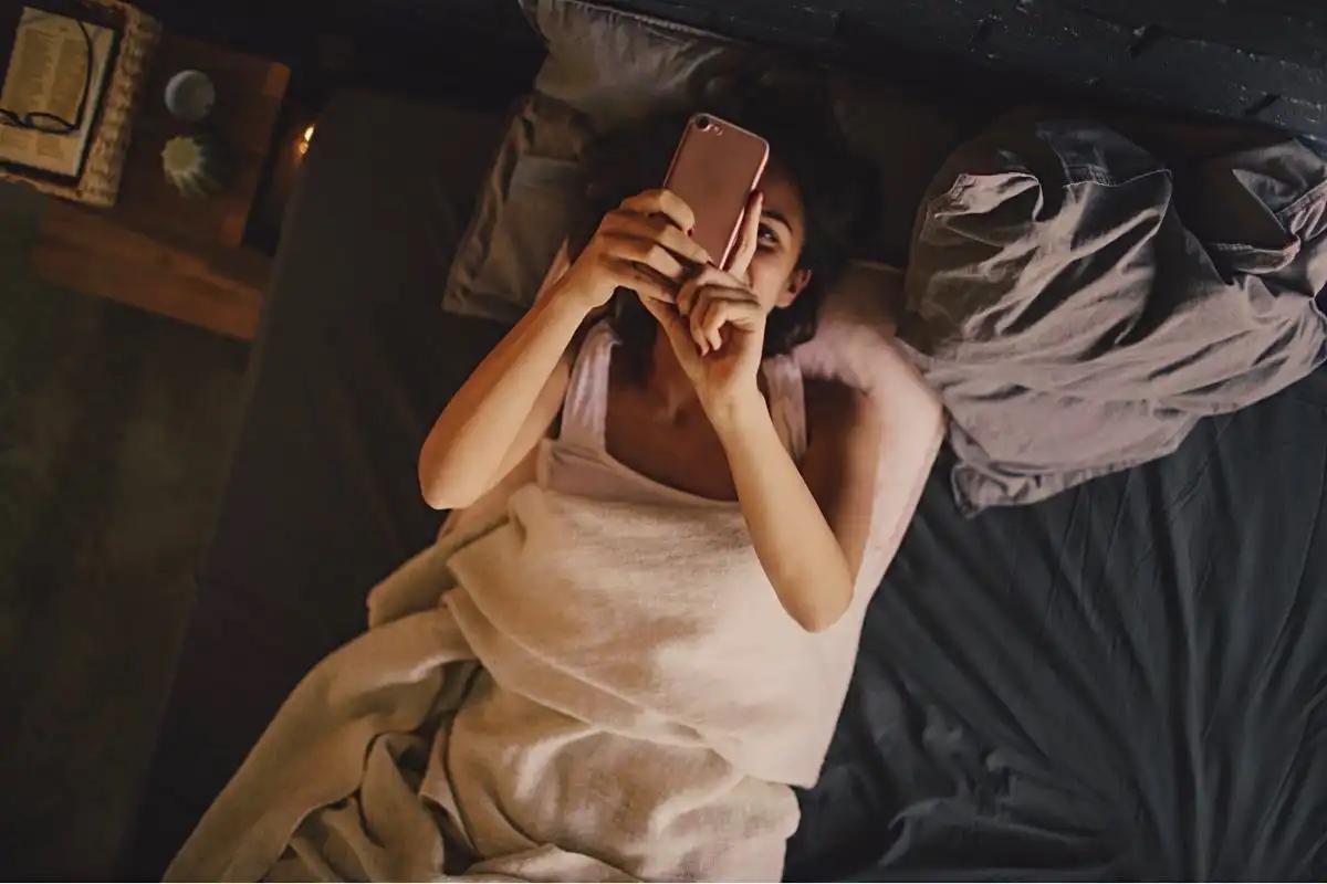 Person in bed looking at their mobile phone - Happy Mind Training Blog | Why We All Need Routine